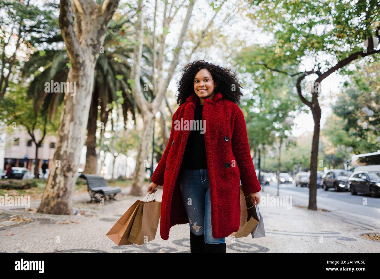Portrait carefree young woman with shopping bags on urban sidewalk Stock Photo