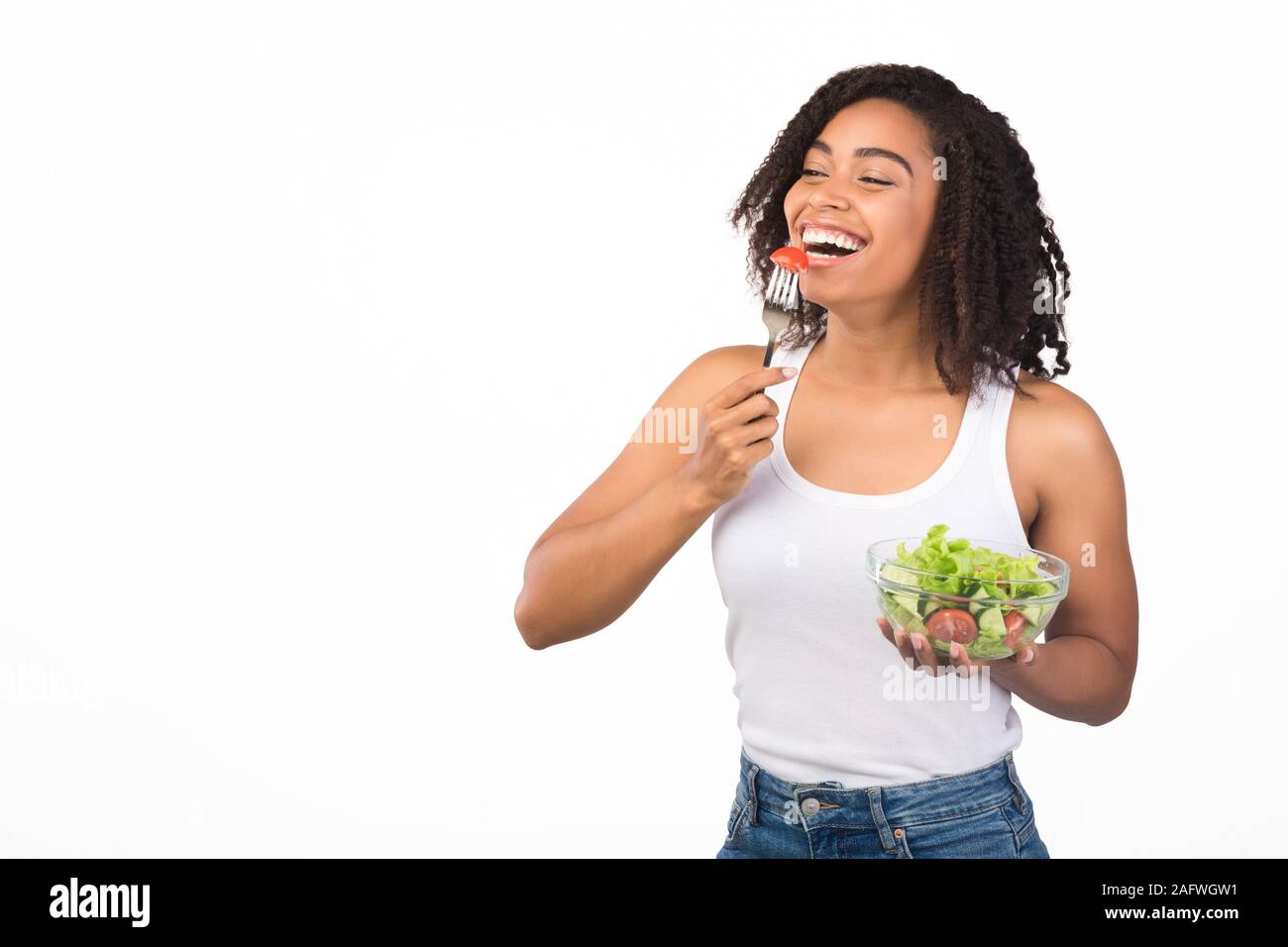Cheerful young black girl eating salad with fork Stock Photo Alamy