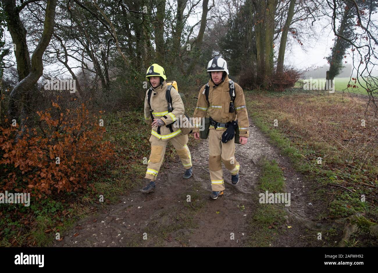 Firefighters Shaun Challis (right) and Lee Smith from West Sussex Fire and Rescue service, walk along the South Downs Way near to Winchester in Hampshire, as they set out on a charity walk to Eastbourne, wearing full fire kit, raising money for Martlets Hospice and The Fire Fighters Charity. Stock Photo