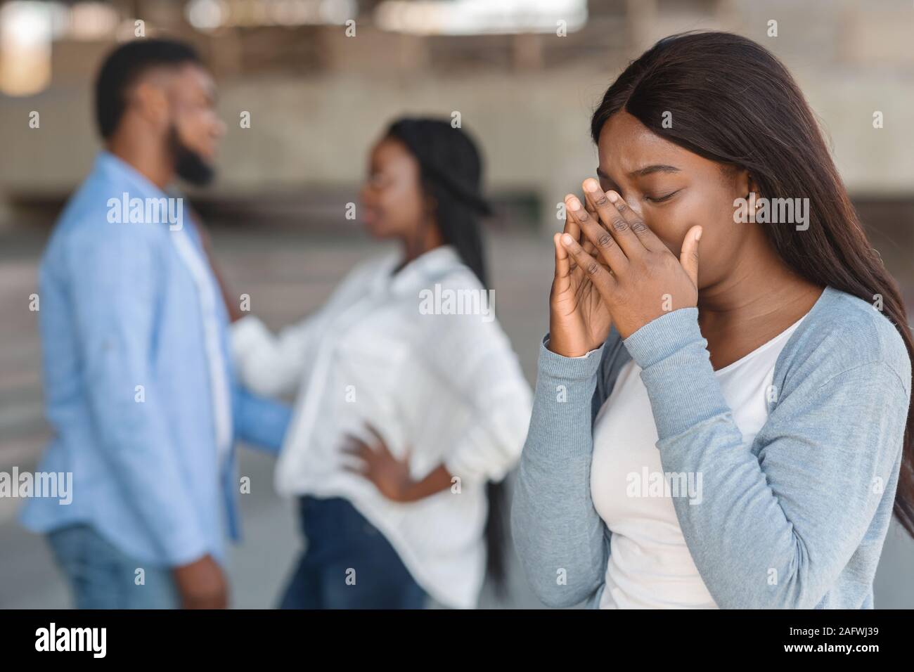 Young girl crying watching her ex boyfriend happy with another woman Stock Photo