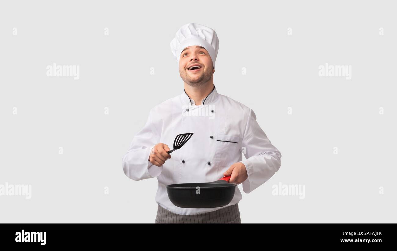 Cook Man Holding Pan And Spatula Looking Up, White Background Stock Photo