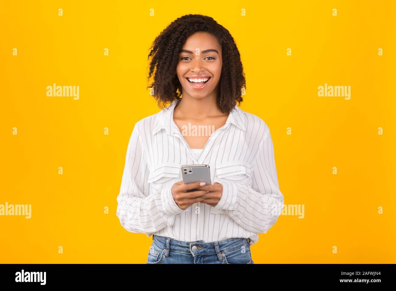 Smiling black girl using iPhone 11 pro max Stock Photo