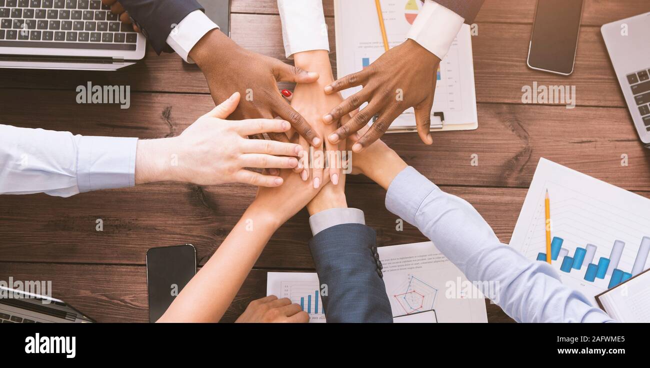 Multiethnic coworkers stacking hands together in office Stock Photo - Alamy