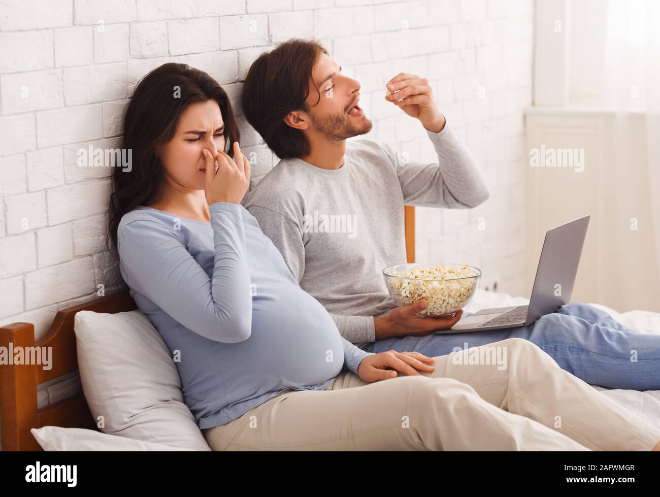 Pregnant woman closing nose, feeling sick with nausea beause of smell Stock Photo