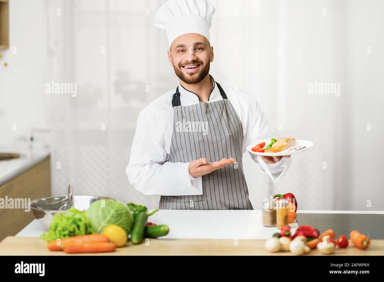 Chef Man Holding Plate Presenting Dish Standing In Kitchen Indoor Stock Photo