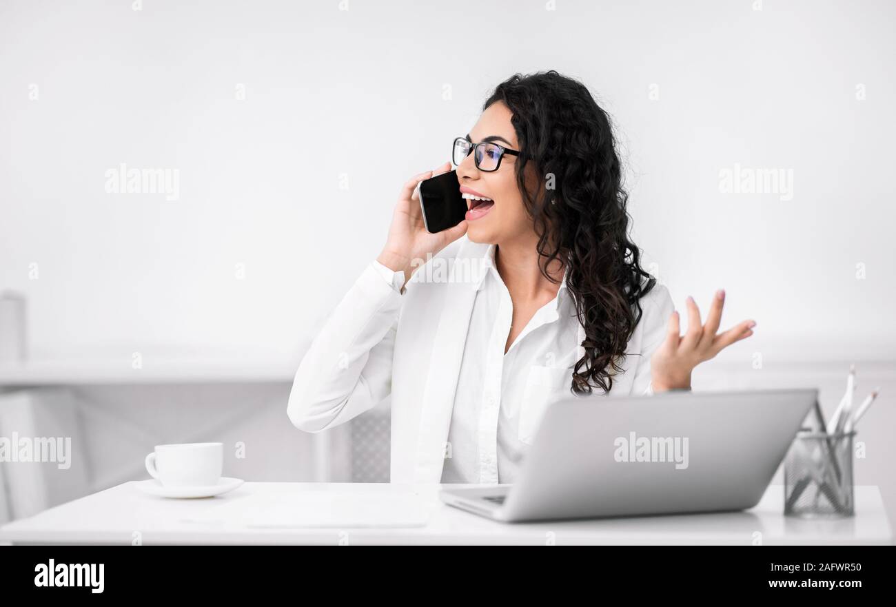 Mexican woman talking on cell phone at office Stock Photo - Alamy