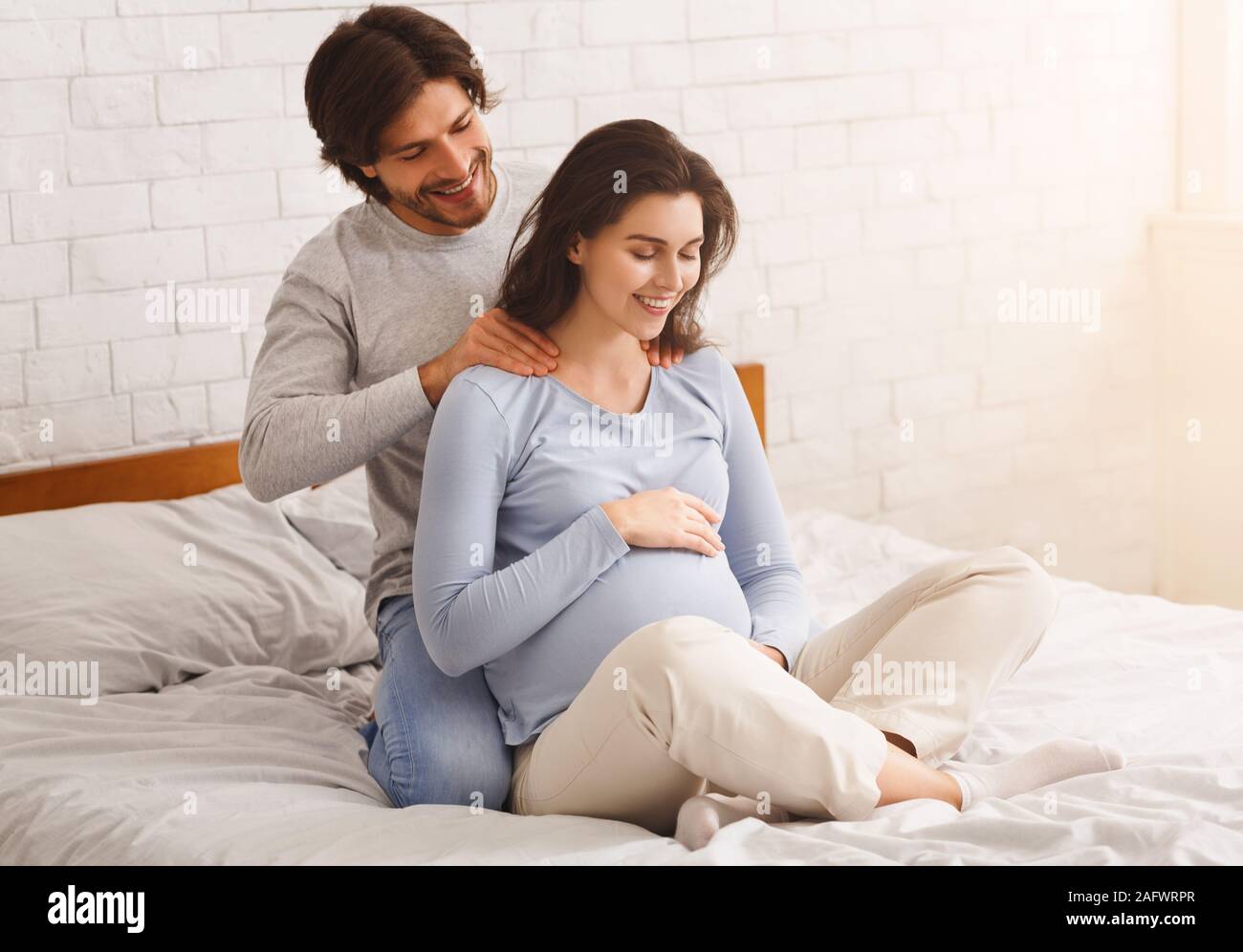 Loving husband making back massage to his happy pregnant wife Stock Photo