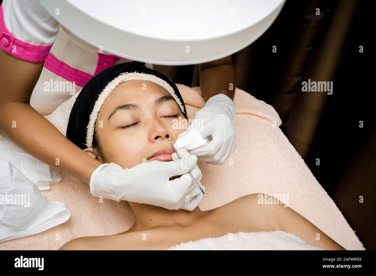 Southeast Asian young woman having facial treatment by beautician. Removing  blackheads which clog the pores Stock Photo - Alamy