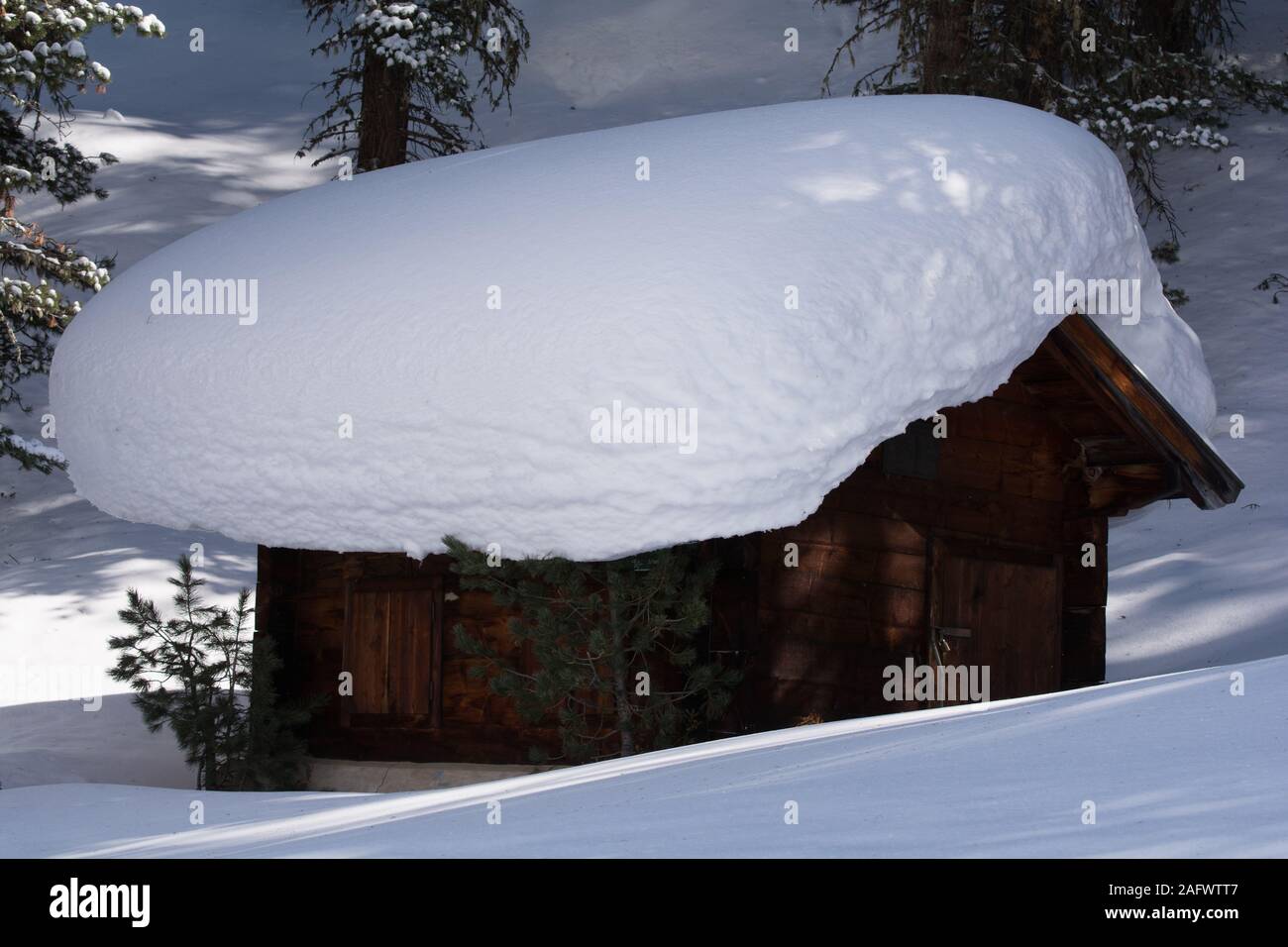 Wooden hut with massive snow layer on the roof. Near the Kaunertal ski resort road, Tyrol, in the Austrian Alps. Stock Photo