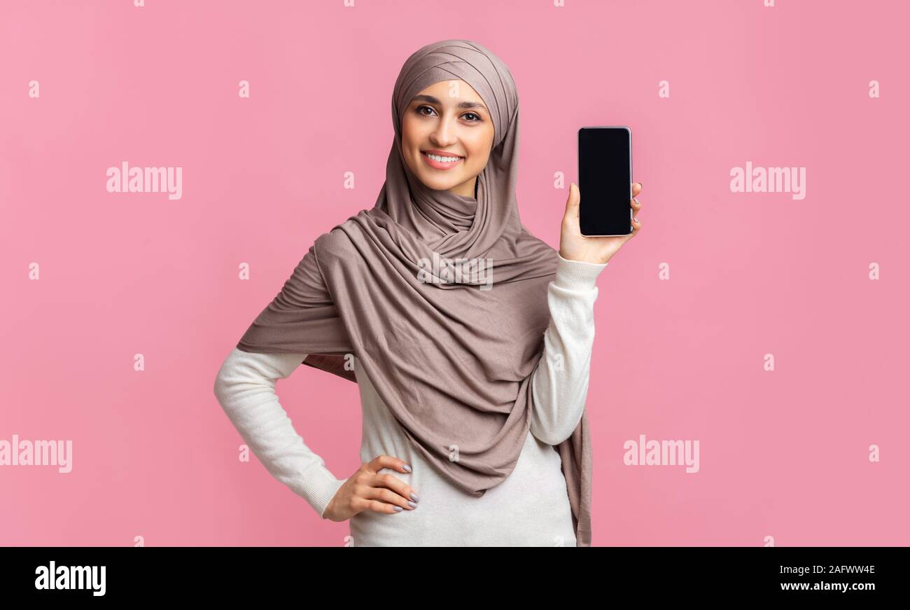 Muslim girl in headscarf showing modern smartphone with black screen Stock Photo
