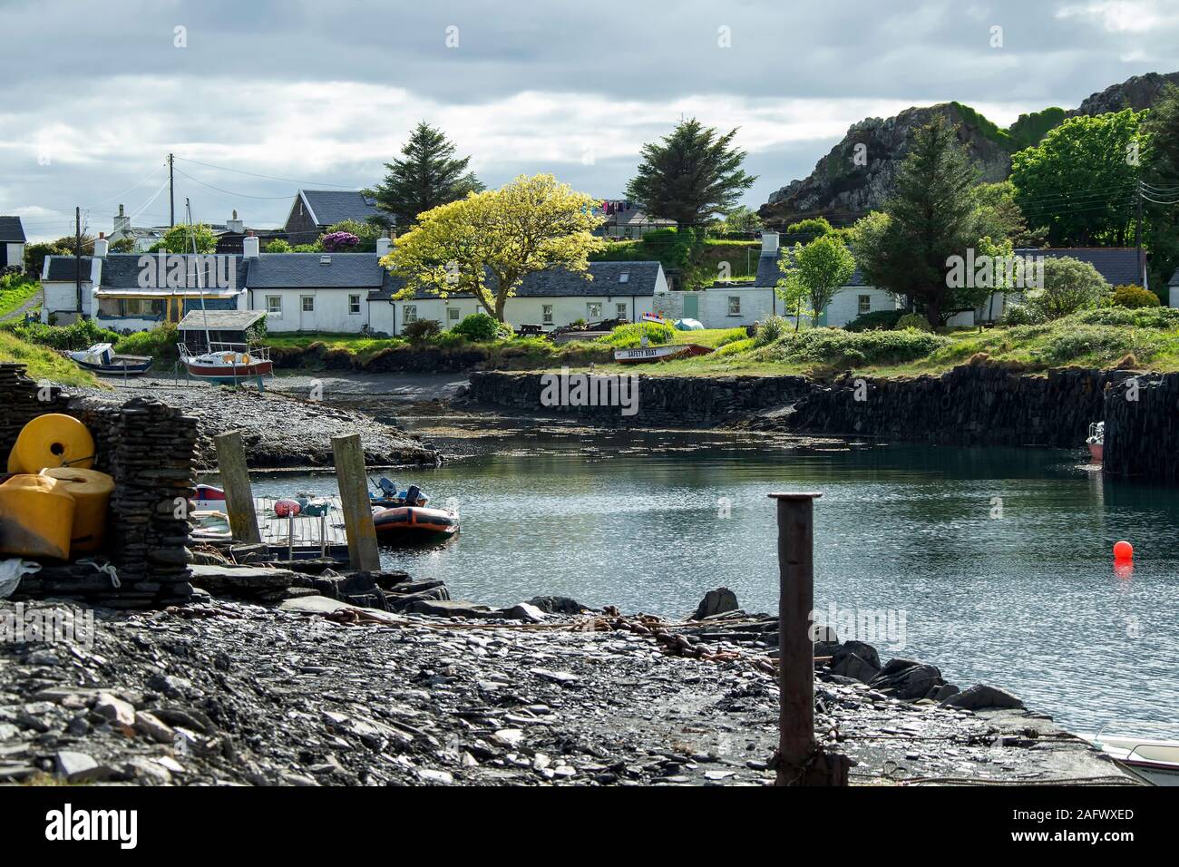 The harbour on Easdale Island off the West Coast of Scotland showing Slate Workers' Cottages with rugged hills behind. Stock Photo
