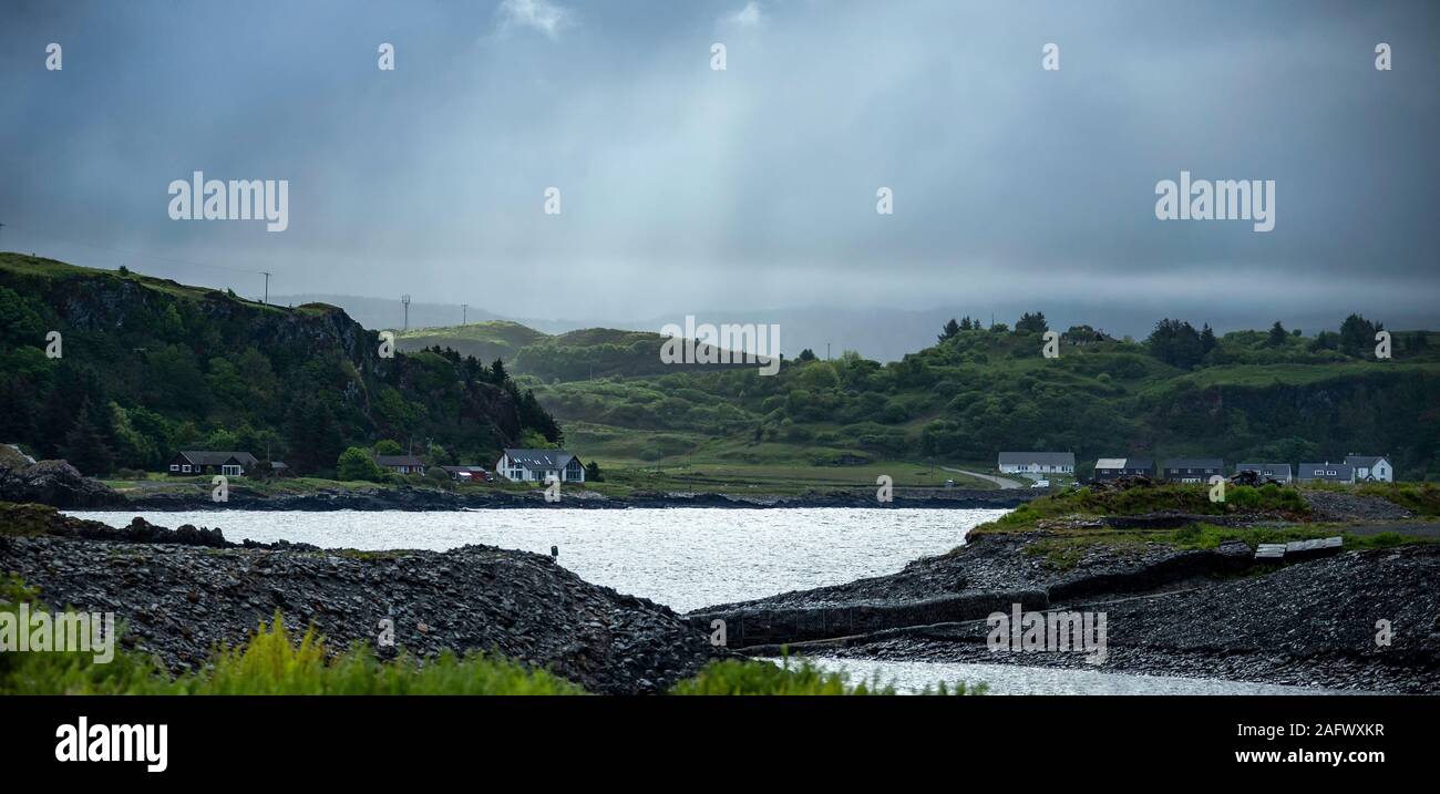 Glowering skies and rain on the hills - Looking back towards the harbour of Ellenabeich, a small village on the isle of Seil  from Easdale Island. Stock Photo