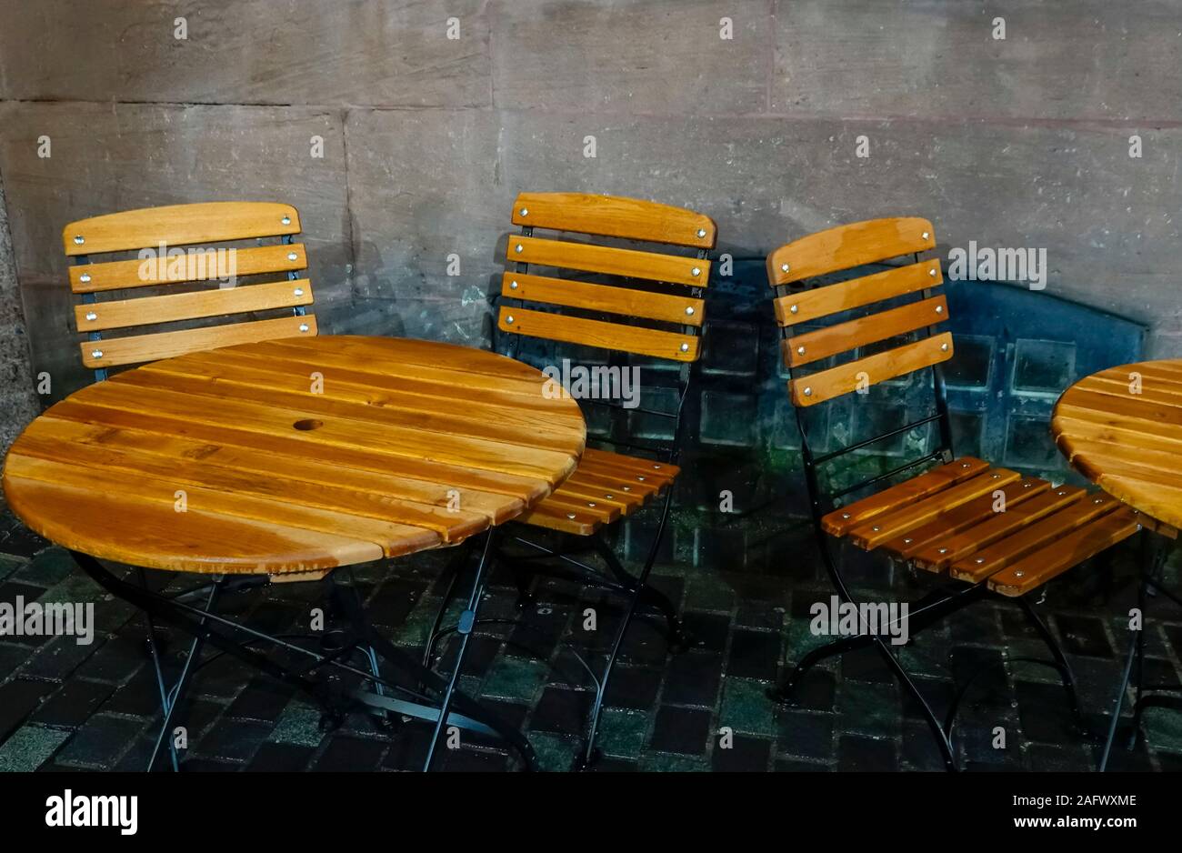 Wooden tables and chairs outside a cafe in the rain in Liverpool Stock