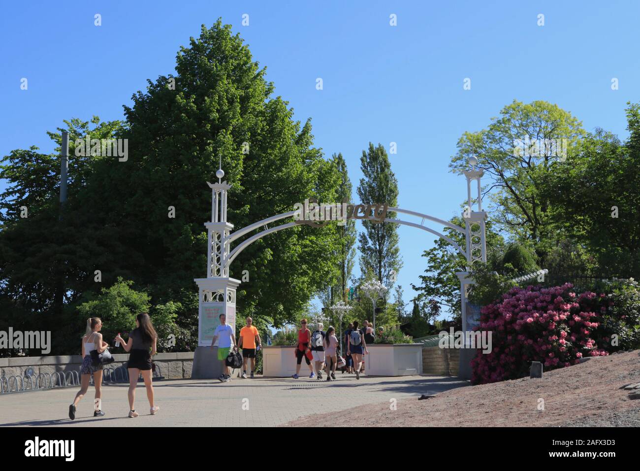 People walk along the promenade to the entrance and exit of Liseberg amusement park in Gothenburg city centre, Sweden, during the summer. Stock Photo