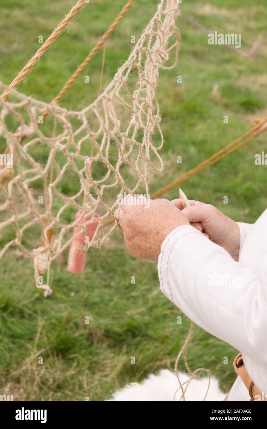 A woman making a medieval fishing net using traditional bone tools