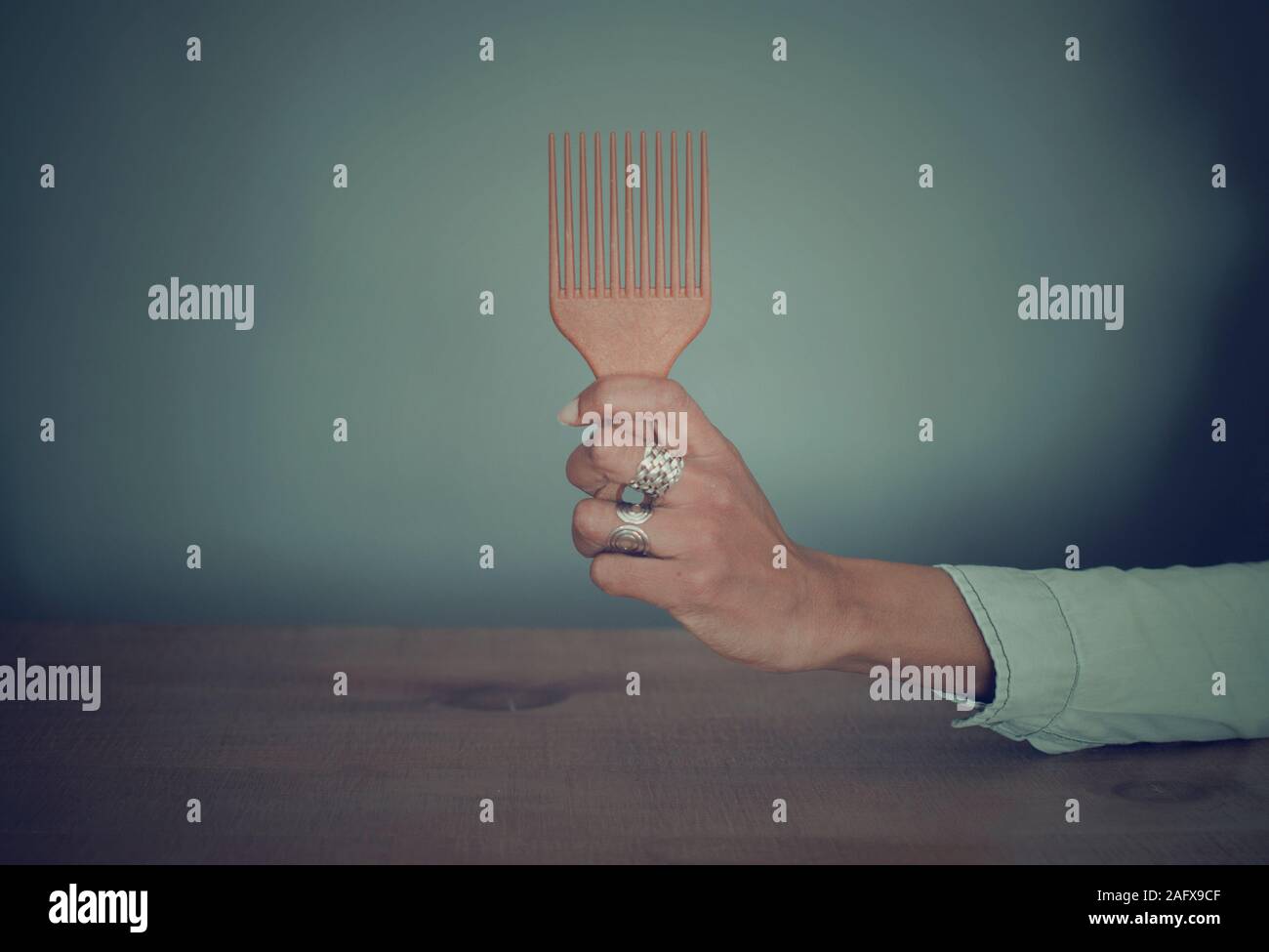 Selective focus on the hand (with rings) of a black woman holding an afro comb Stock Photo