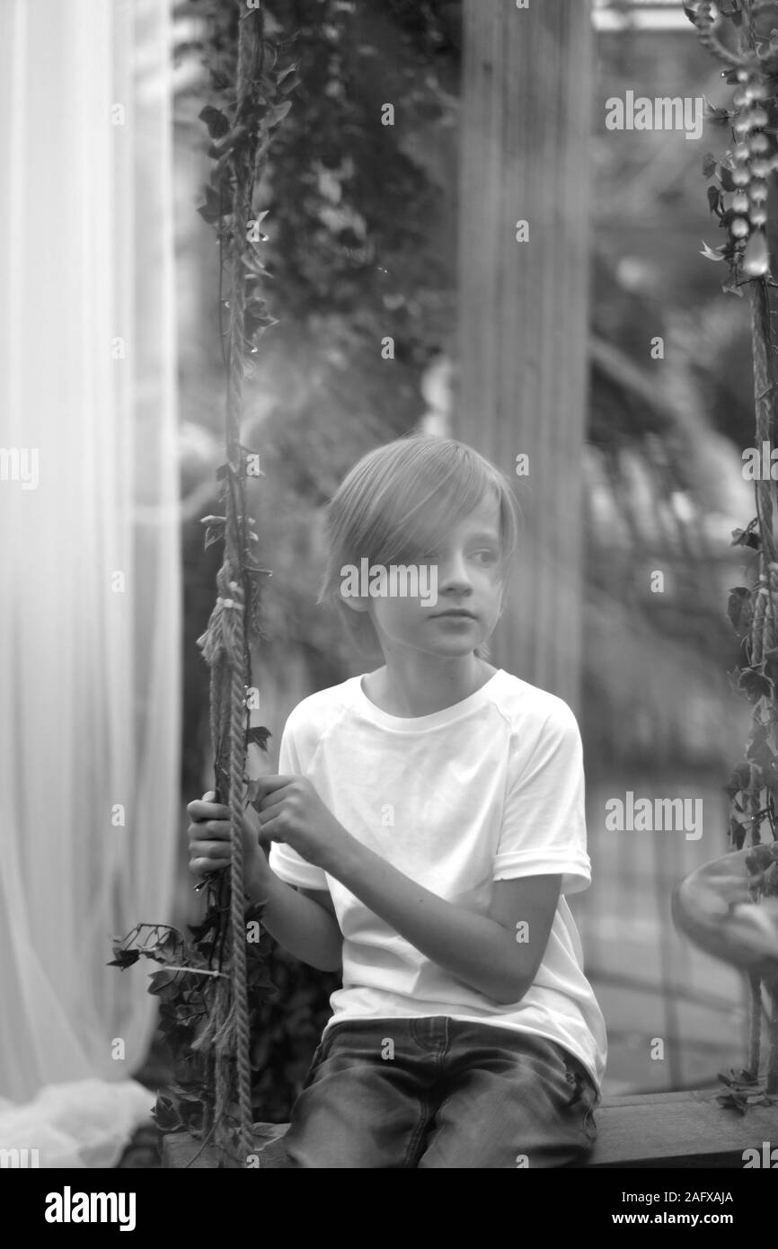 A child is sitting on a swing in a decorated pavilion Stock Photo