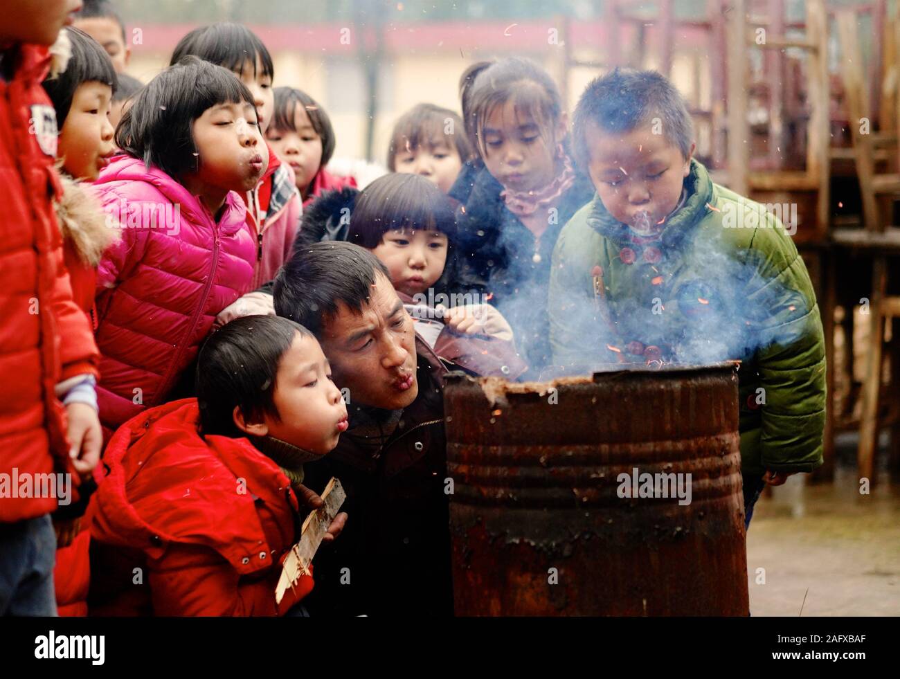 Beijing, China's Jiangxi Province. 3rd Jan, 2019. Teacher Zhang Zhanliang (R, front) and his students blow to make a fire at Huangni Primary School in Chuntao Town of Yingtan City, east China's Jiangxi Province, Jan. 3, 2019. Zhang Zhanliang has served as the principal of the school since September 2018. There was no canteen at the rural school, where most of the students were left-behind children. Zhang spent his own money buying food materials and made meals for the students. A collection of heartwarming moments in 2019 by Xinhua photographers. Credit: Hu Chenhuan/Xinhua/Alamy Live News Stock Photo