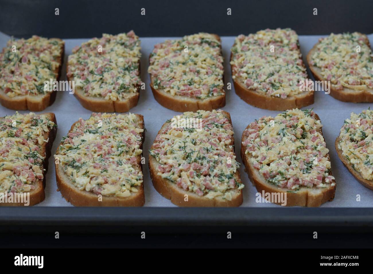 Homemade sandwiches with cheese and sausage before baking on parchment on a baking sheet, the cooking process, Horizontal orientation Stock Photo