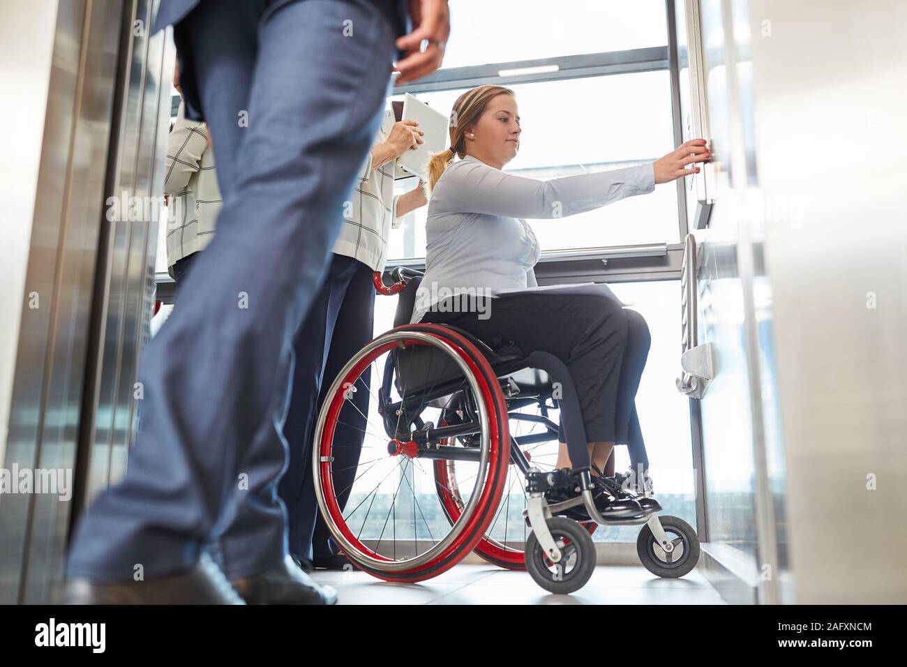 Woman as a wheelchair user presses elevator button for inclusion and