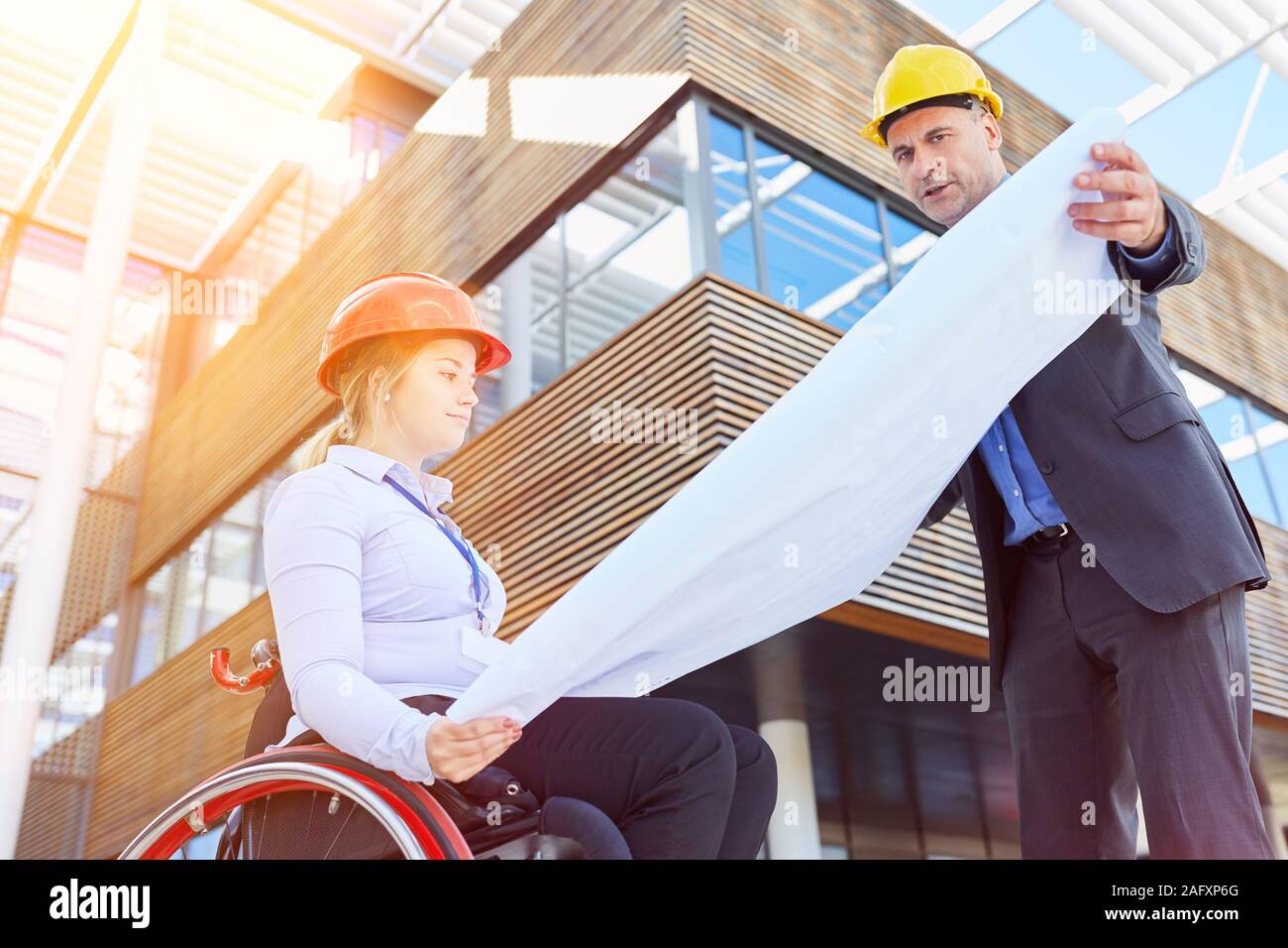 Woman in a wheelchair has construction management during construction planning as an inclusion concept Stock Photo