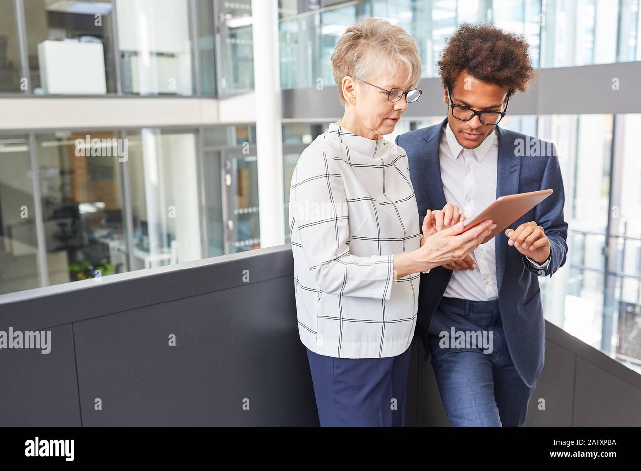 Senior and trainee research together on the Internet using tablet computers Stock Photo
