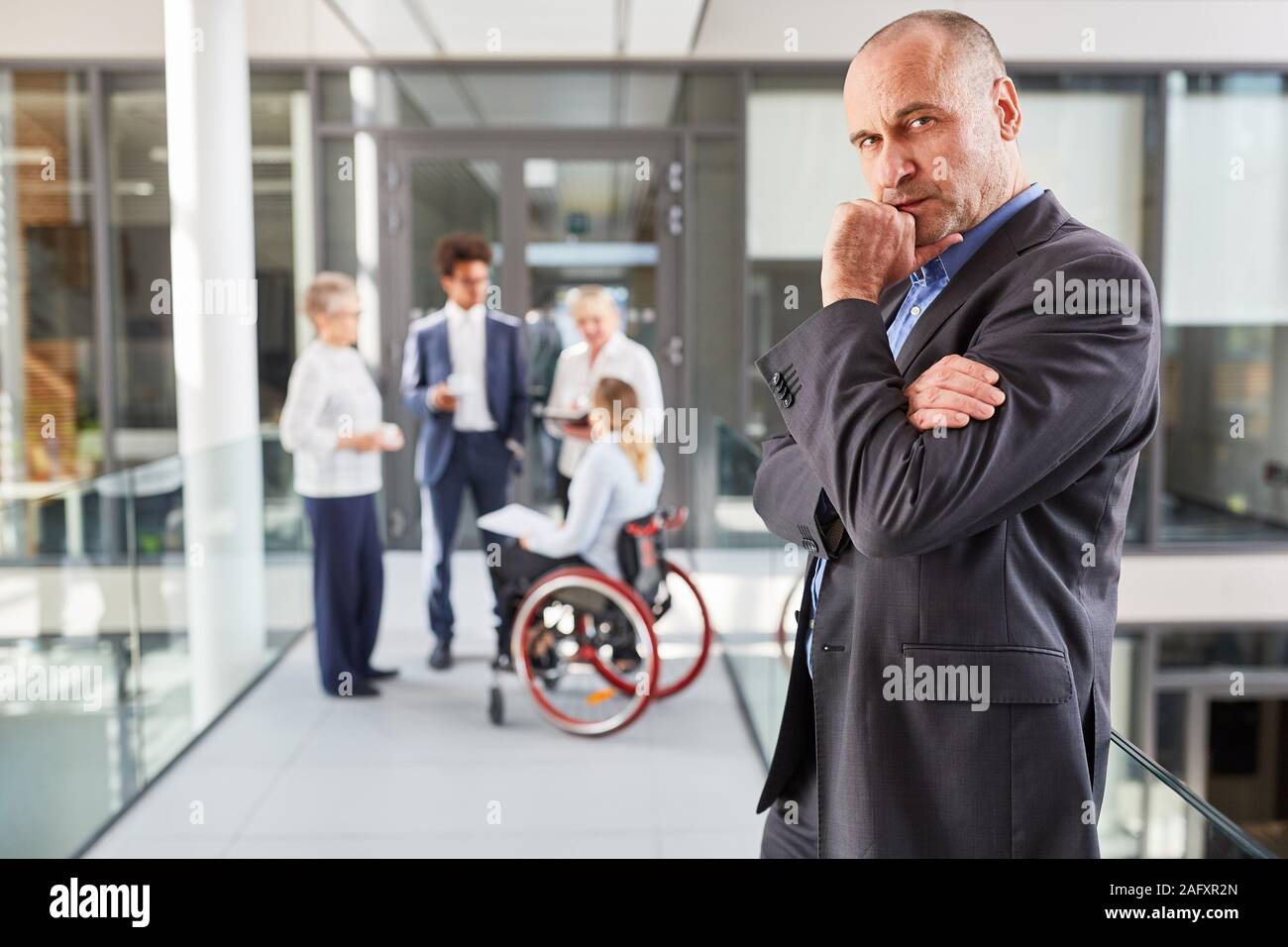 Thoughtful manager with a wheelchair user in the team for inclusion and difficulty Stock Photo