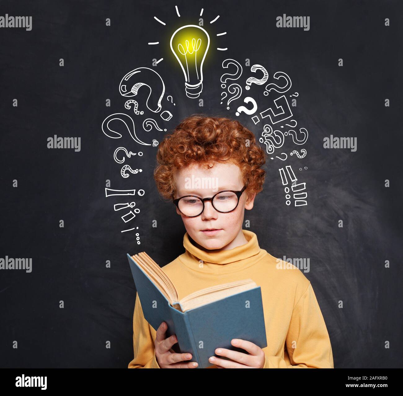 Child reading on blackboard background with lightbulb Stock Photo