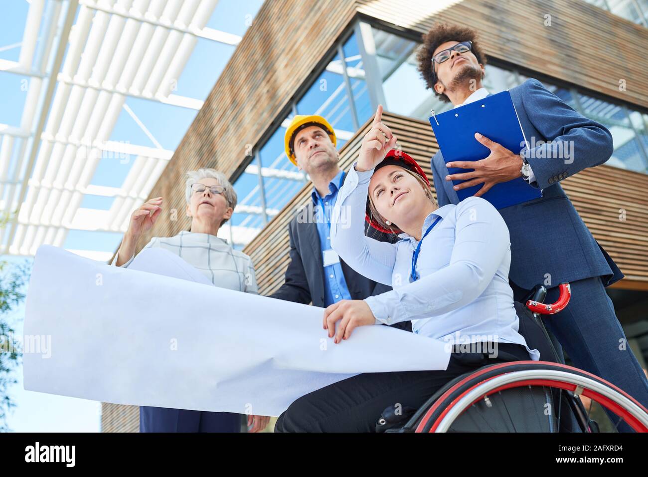 Architect in a wheelchair and engineering team are planning a barrier-free construction project Stock Photo