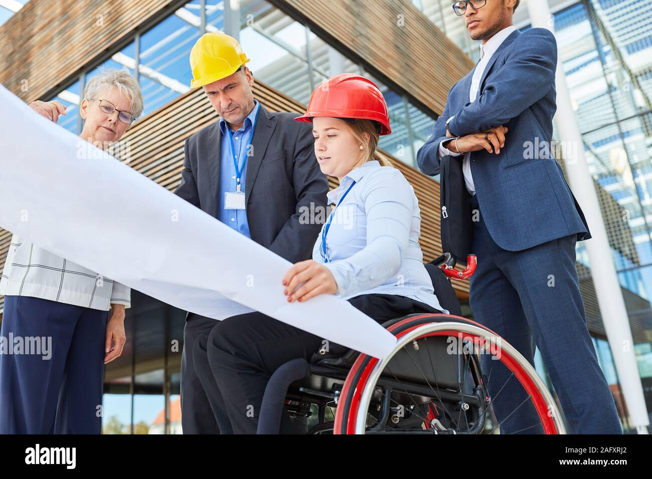 Disabled architect in a wheelchair and engineers in the team during construction planning Stock Photo
