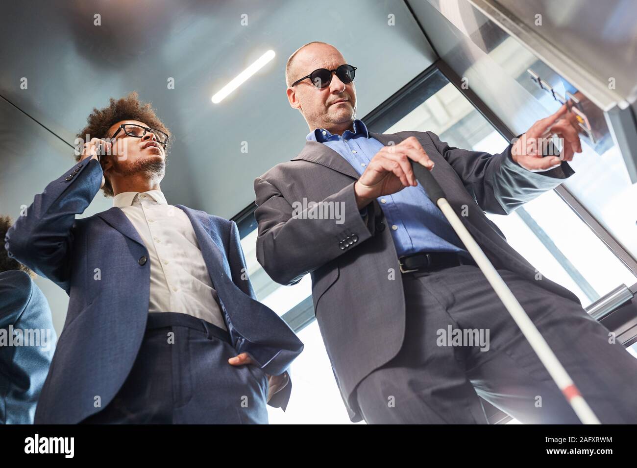 Blind man presses button in the elevator from the office Stock Photo