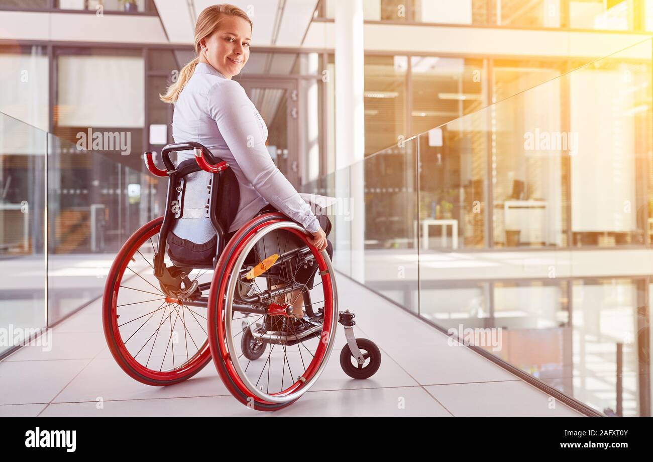 Smiling disabled businesswoman in wheelchair in office as inclusion ...