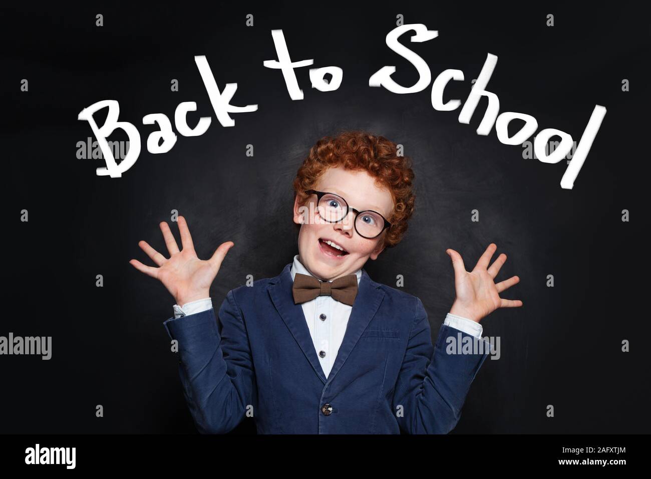 Funny scared child boy on blackboard background. Back to school concept Stock Photo