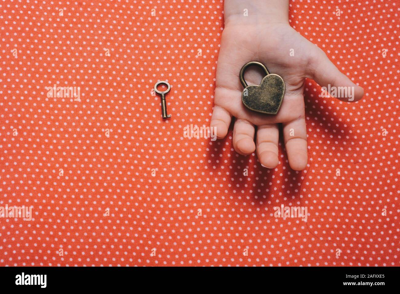 Hand holding a heart shaped lock and key on a red background Stock ...