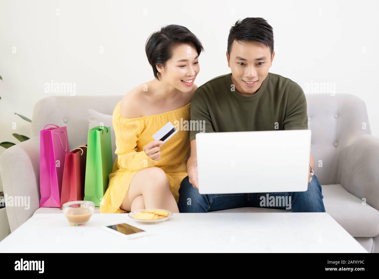 Young Asian Couple Making Online Purchases On Laptop At Home Stock Photo