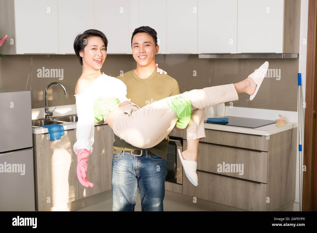 Young Asian couple cleaning the kitchen and having fun. Home cleaning and hygiene concept Stock Photo