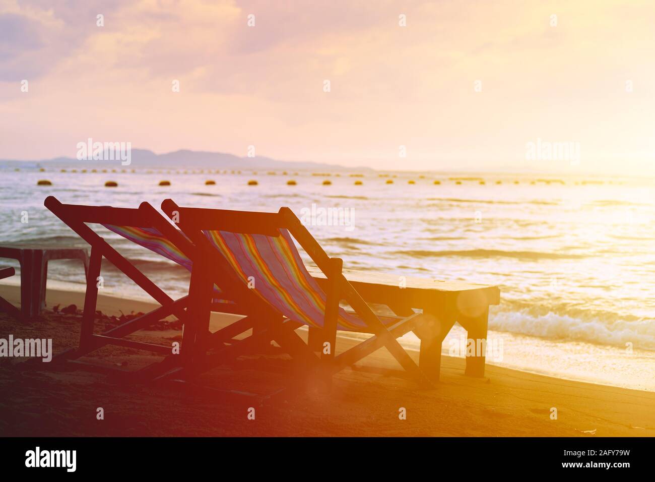 couple bed chair set on the beach with sun twilight calm sunset sky background. Stock Photo