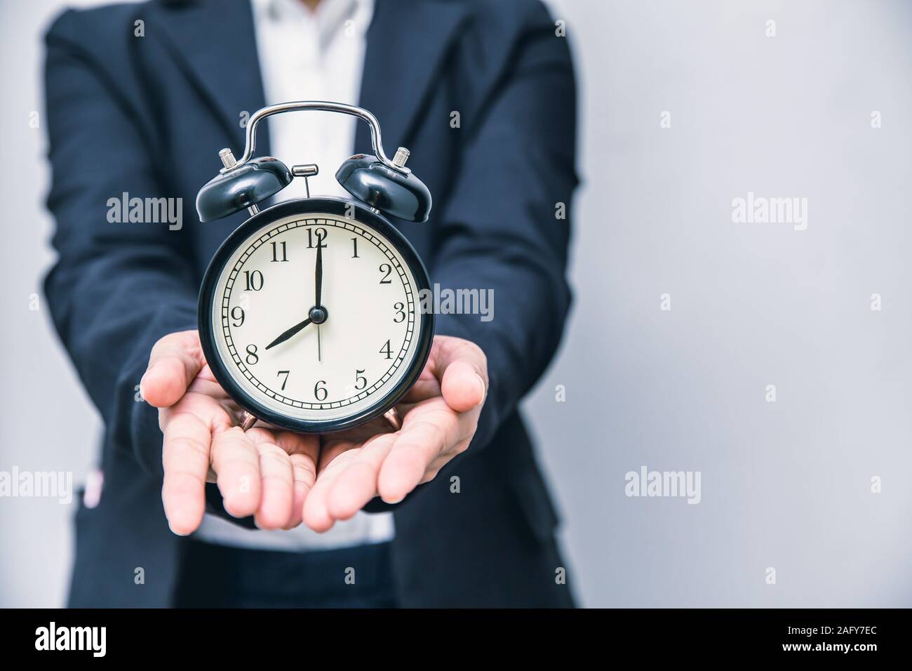 Give a Times concept. Time clock in business people hand with space for