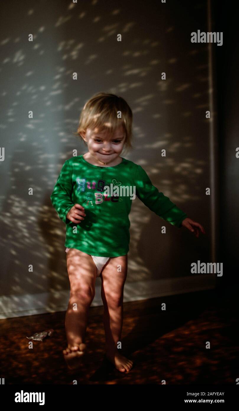 toddler standing in sparkling sunlight in hallway Stock Photo