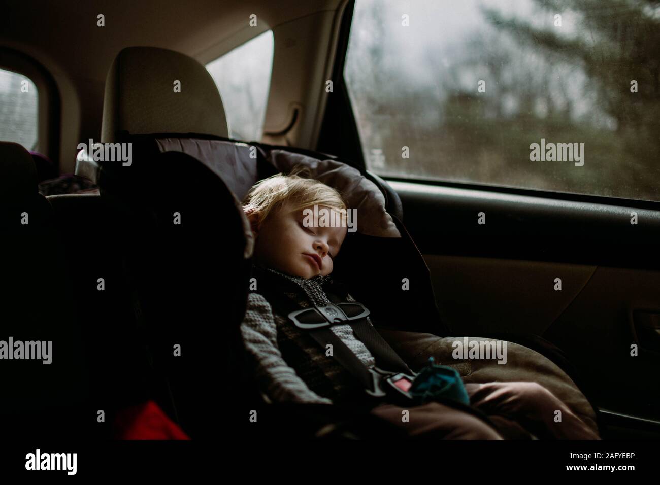 toddler asleep in carseat on road trip Stock Photo