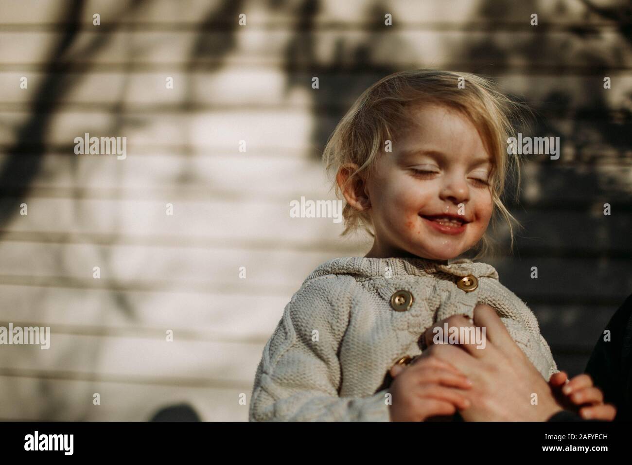toddler smiling with eyes closed in sunlight Stock Photo