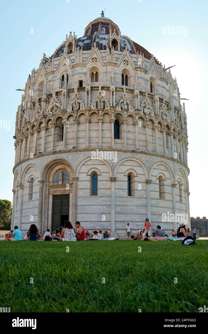 Summer tourists enjoying the Baptistry of St. John / San Giovanni Baptistery in the Piazza dei Miracoli, Pisa Tuscany Italy EU Stock Photo