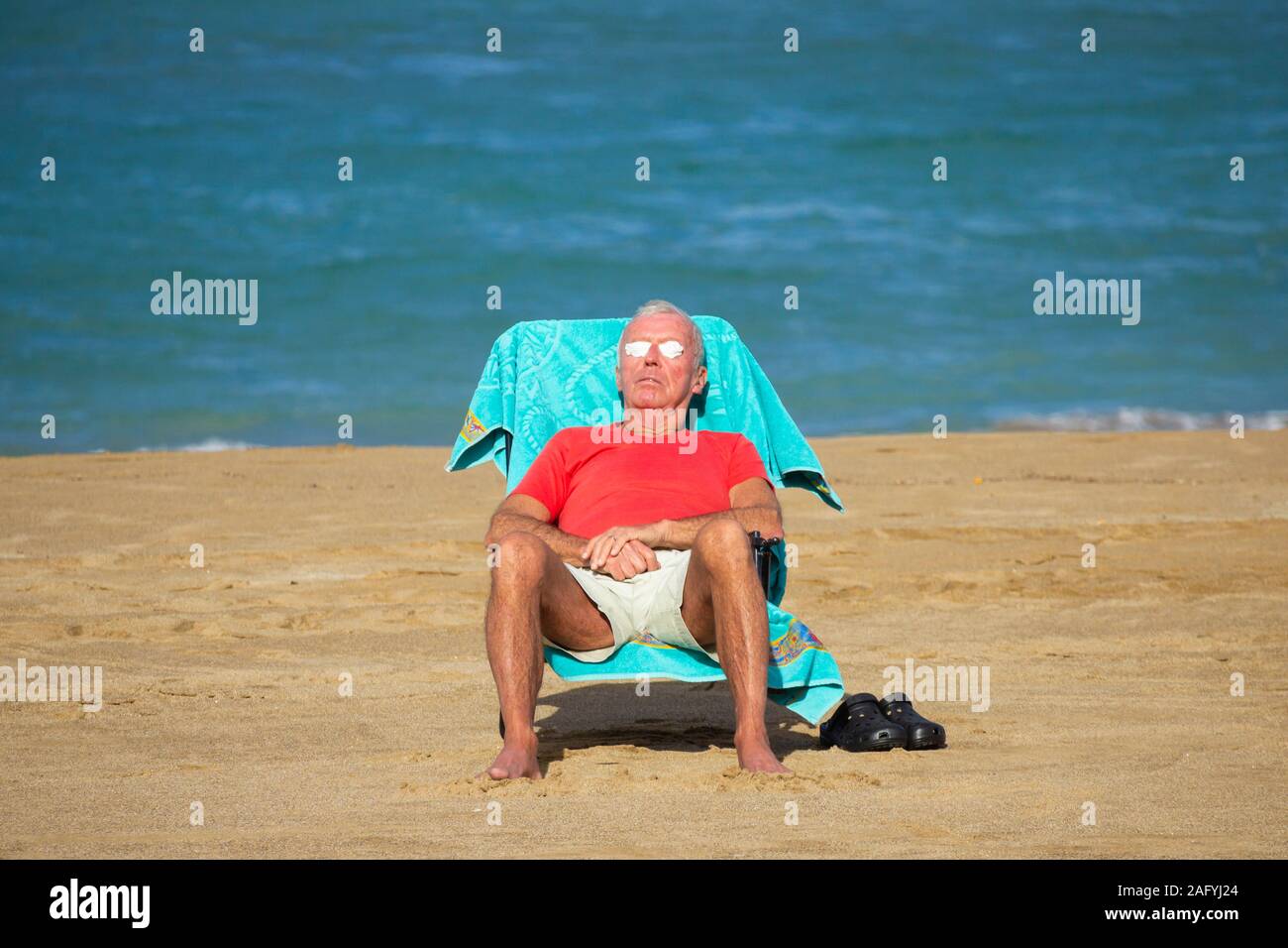 elderly-old-man-sunbathing-on-beach-2AFYJ24.jpg