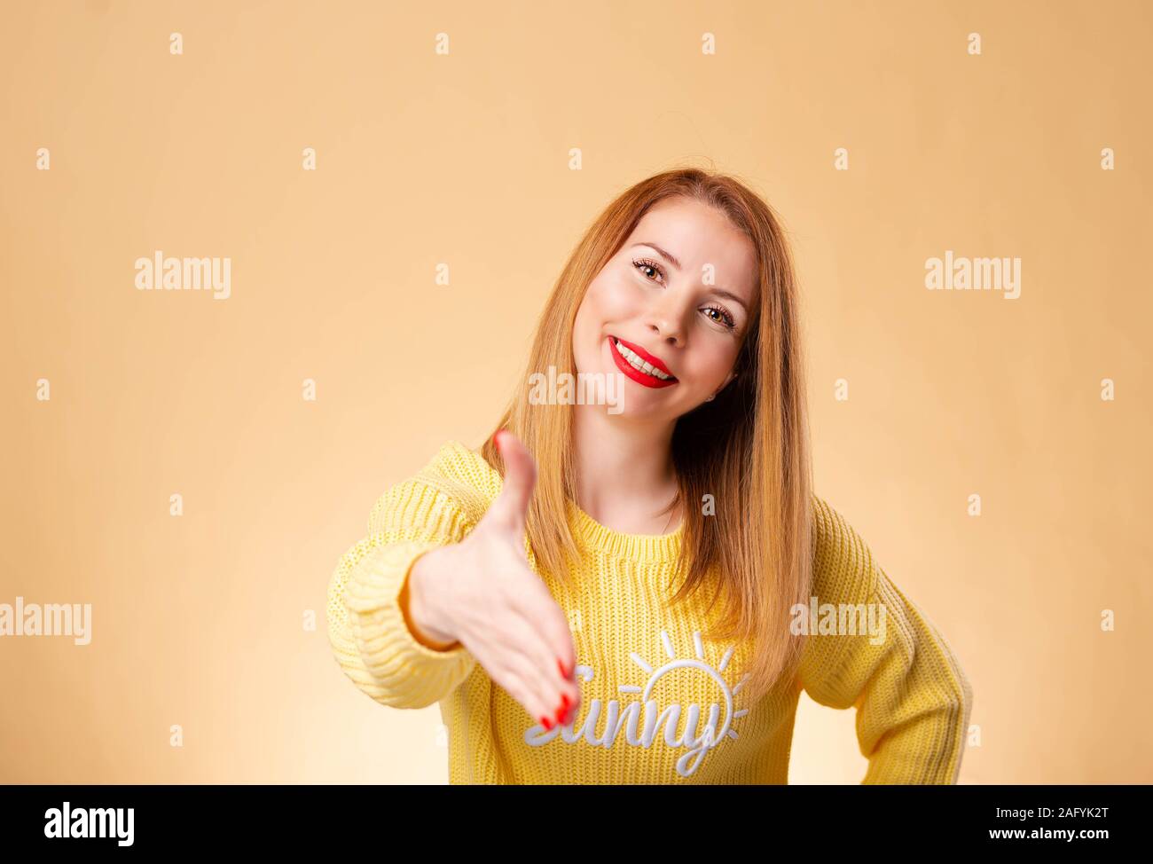 Young beautiful woman wearing casual t-shirt standing over isolated white background smiling friendly offering handshake as greeting and welcoming Stock Photo