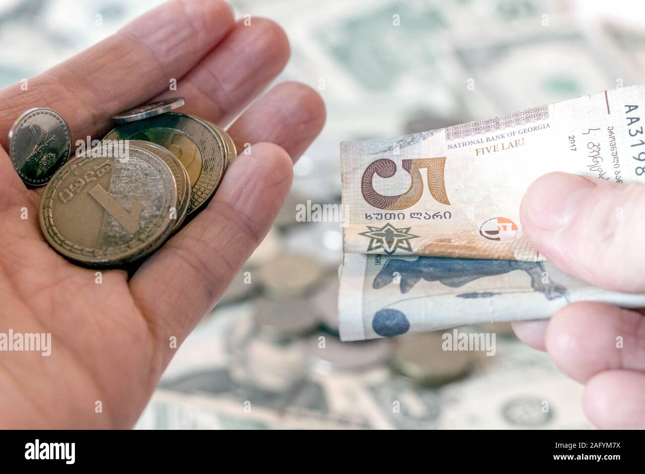 Hand holding georgian lari coins and banknotes against usd american dollar background with russian ruble rub coins. International currency and economy Stock Photo