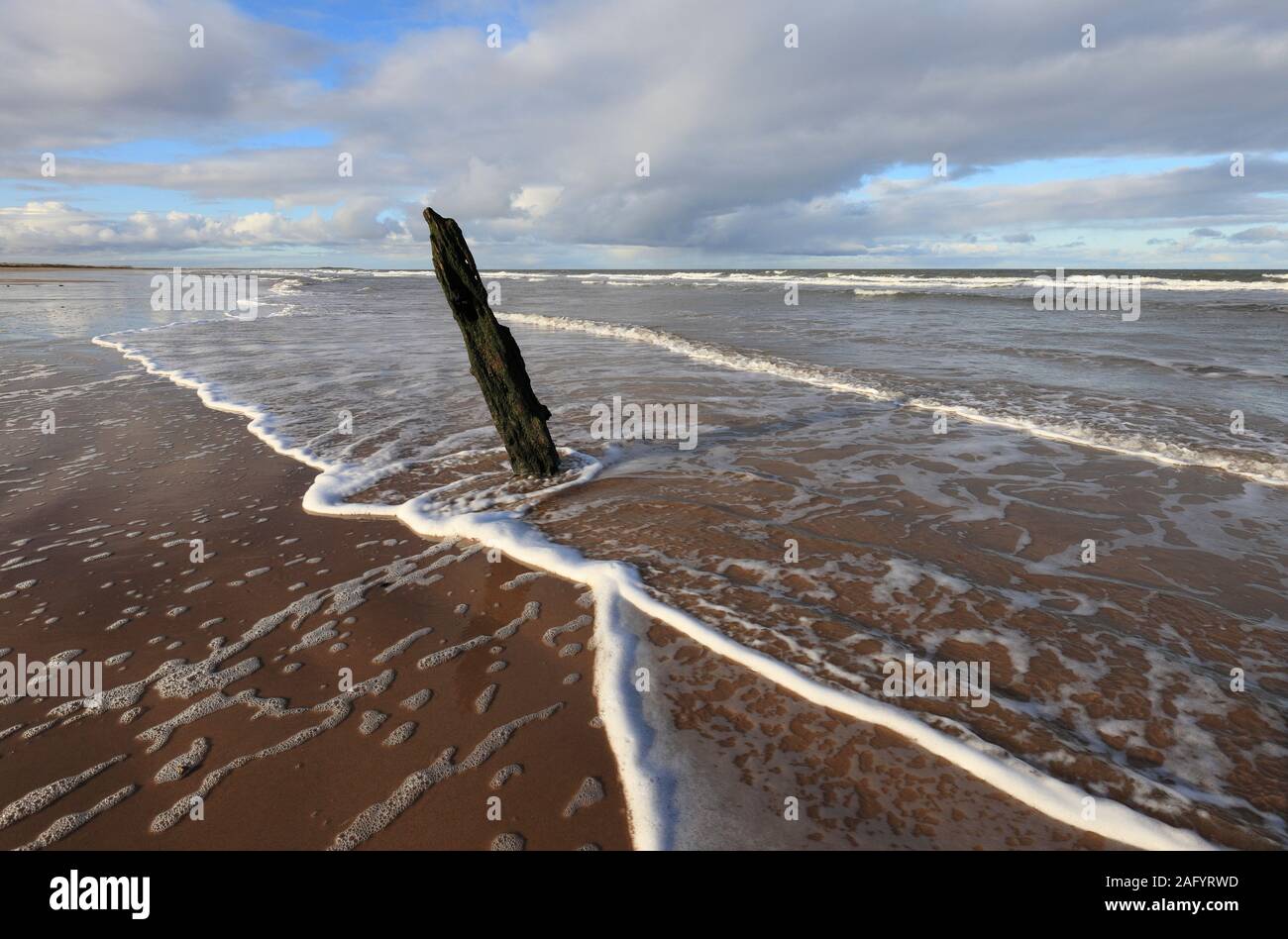 Old wooden post on Brancaster beach, North Norfolk. Stock Photo