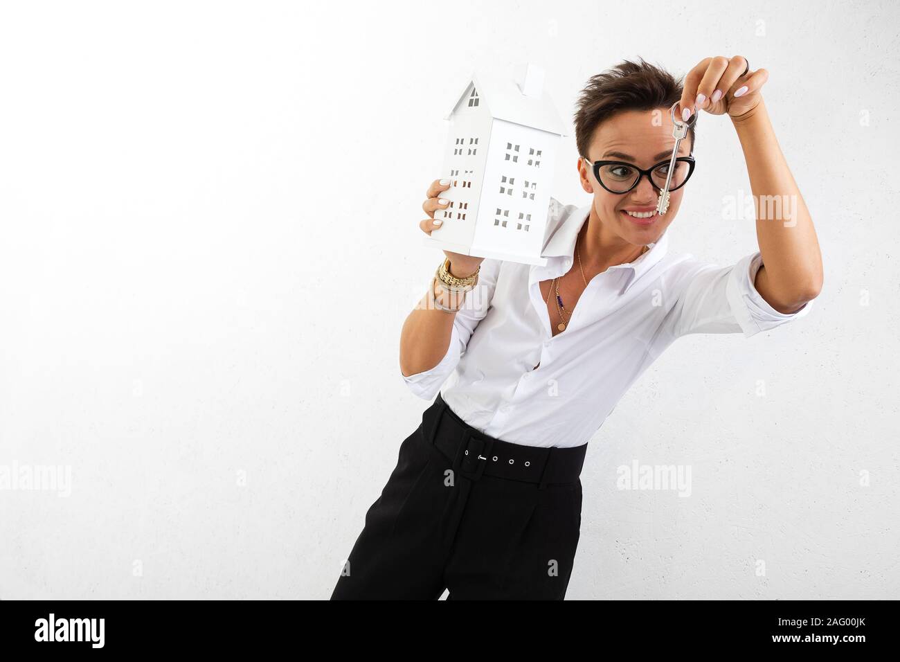 young woman with house model and keys on white background Stock Photo ...