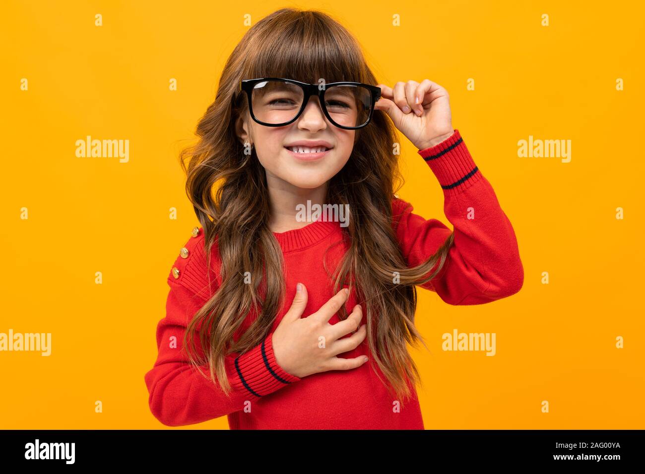 cute little girl in glasses squints on an orange background Stock Photo ...