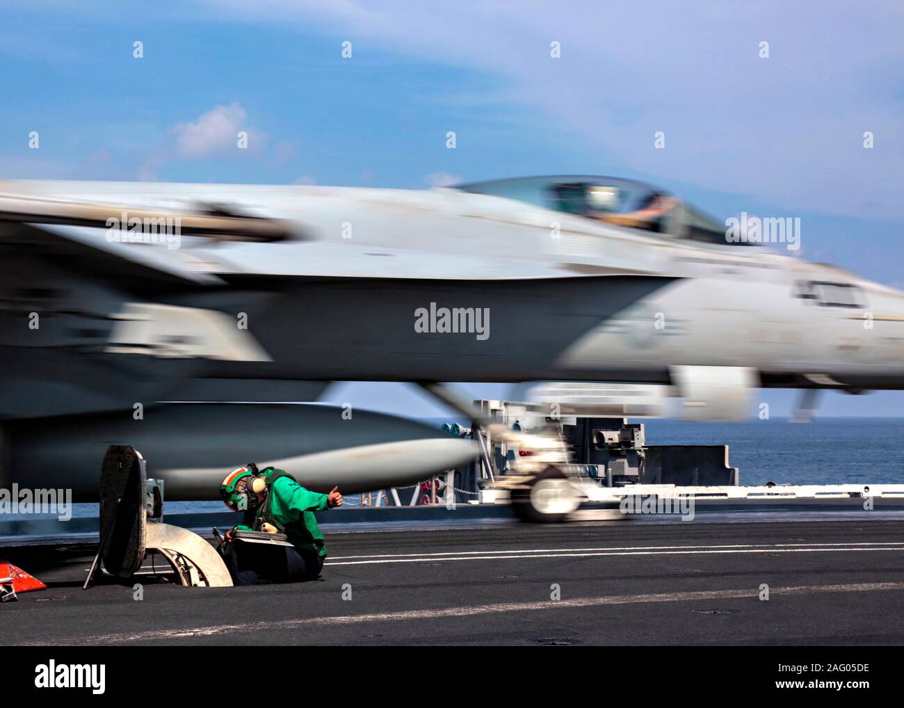 U.S. Navy sailor Jessie Rose gives a thumbs up as he launches a Navy F/A-18E Super Hornet fighter aircraft from the flight deck of the Nimitz-class aircraft carrier USS Abraham Lincoln in support of Operation Inherent Resolve December 13, 2019 in the Arabian Gulf. Stock Photo
