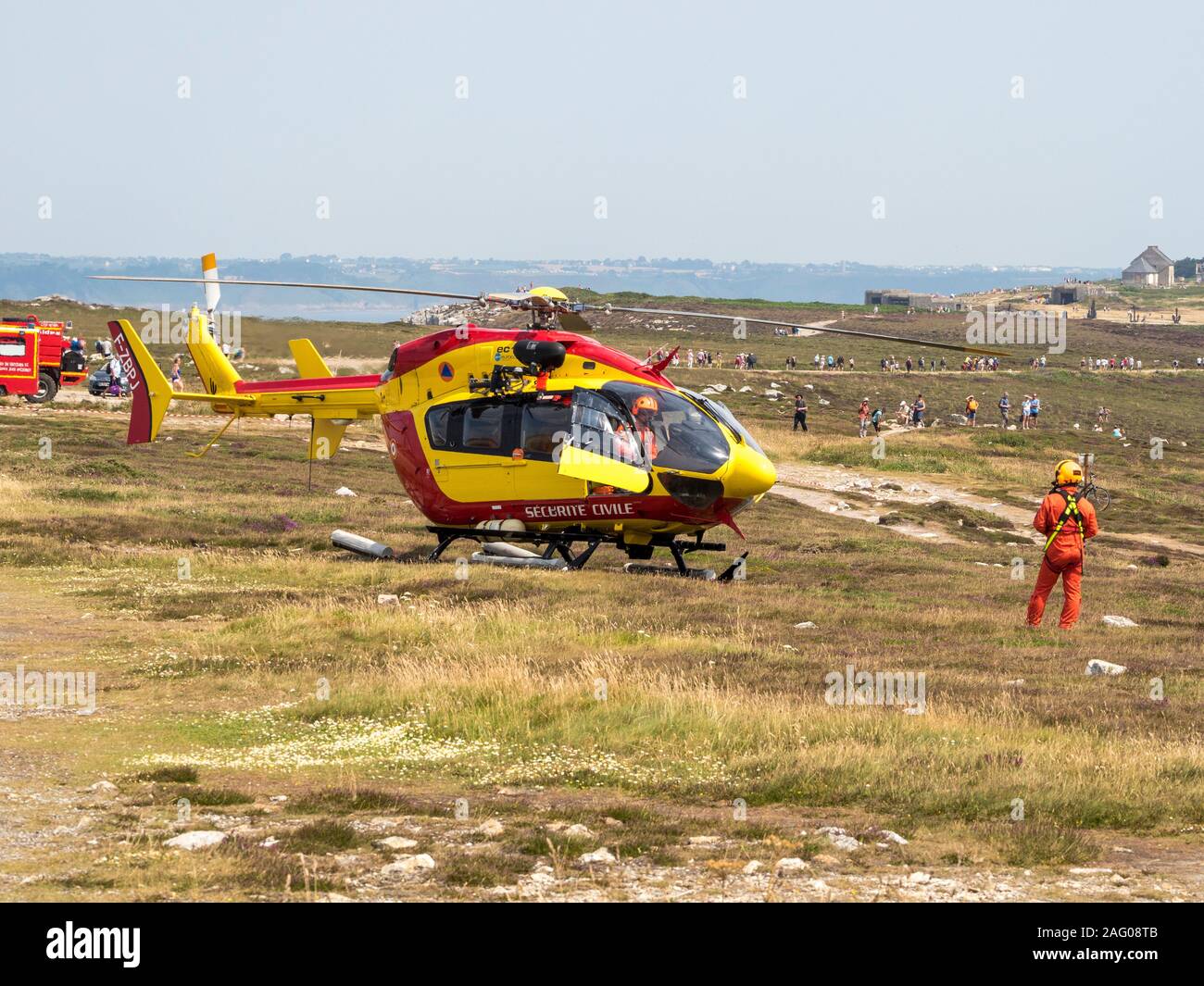 Civil security helicopter landed. One crew member in the cabin and the other standing in front of the aircraft. France Stock Photo